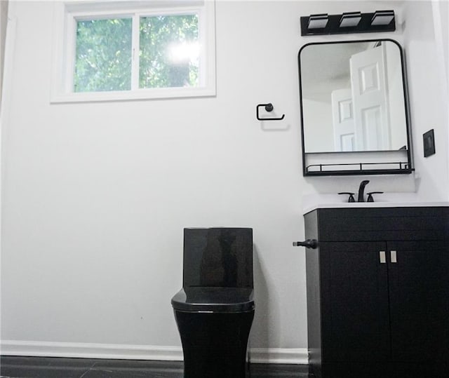 2243 Spruce Ave, Kansas City, MO 64127 - bathroom with baseboards, vanity, and toilet