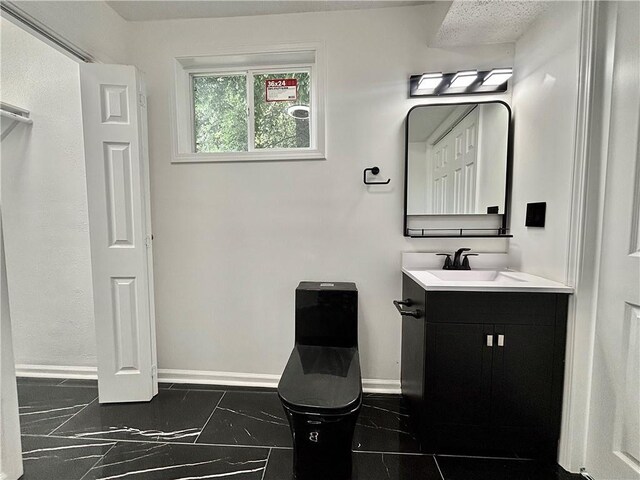 2243 Spruce Ave, Kansas City, MO 64127 - bathroom with vanity, baseboards, marble look tiles, and toilet