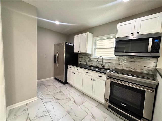 2243 Spruce Ave, Kansas City, MO 64127 - kitchen featuring appliances with stainless steel finishes, baseboards, a sink, light marble finish flooring, and decorative backsplash