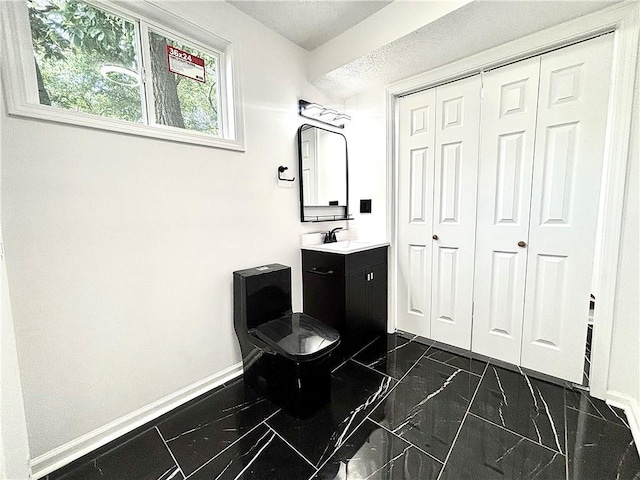 2243 Spruce Ave, Kansas City, MO 64127 - bathroom featuring baseboards, vanity, toilet, a closet, and marble finish floors