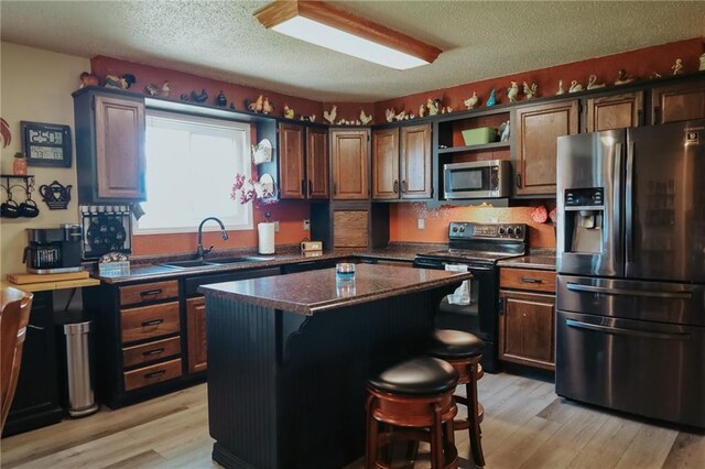 7164 State Route T Hwy, Amazonia, MO 64421 - kitchen featuring appliances with stainless steel finishes, a sink, dark countertops, open shelves, and light wood finished floors