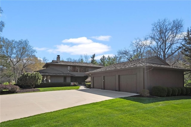 prairie-style home with concrete driveway, a garage, a front yard, and a chimney