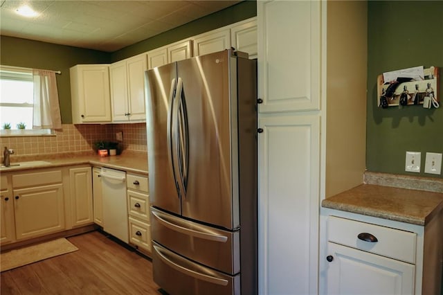 7166 State Route T Hwy, Amazonia, MO 64421 - kitchen with freestanding refrigerator, dishwasher, light wood-style floors, backsplash, and white cabinets
