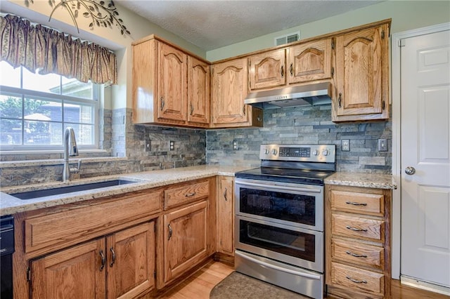 748 SW Windsong Cir, Lees Summit, MO 64082 - kitchen featuring double oven range, a sink, under cabinet range hood, backsplash, and light wood-style flooring