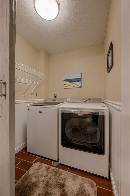 748 SW Windsong Cir, Lees Summit, MO 64082 - laundry area featuring washing machine and clothes dryer, a textured ceiling, dark wood-style floors, and a wainscoted wall