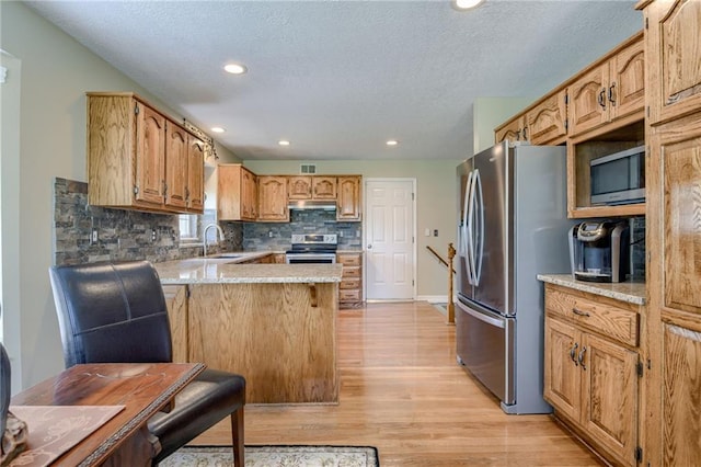 748 SW Windsong Cir, Lees Summit, MO 64082 - kitchen featuring stainless steel appliances, a peninsula, a sink, light wood finished floors, and tasteful backsplash