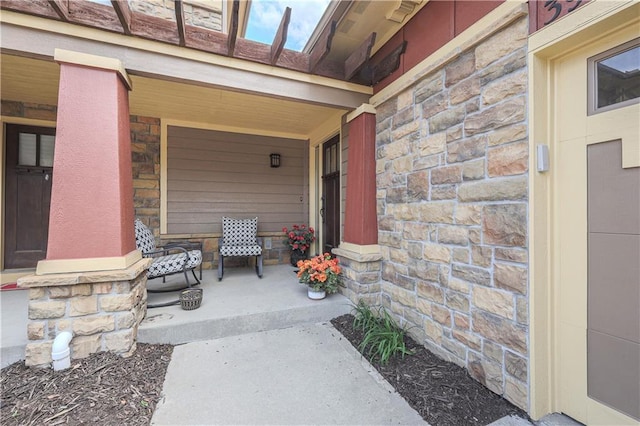 view of exterior entry featuring stone siding and covered porch
