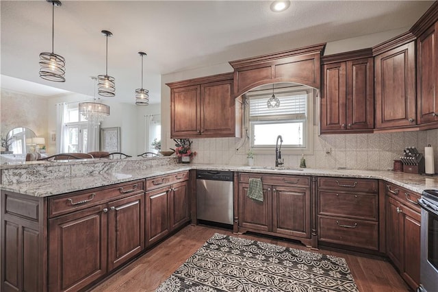 kitchen with appliances with stainless steel finishes, wood finished floors, a sink, and tasteful backsplash