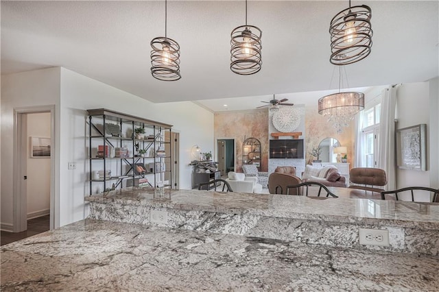kitchen with ceiling fan, a chandelier, hanging light fixtures, light stone counters, and wood finished floors
