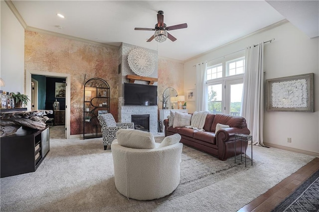 living area with a ceiling fan, a fireplace, baseboards, and crown molding