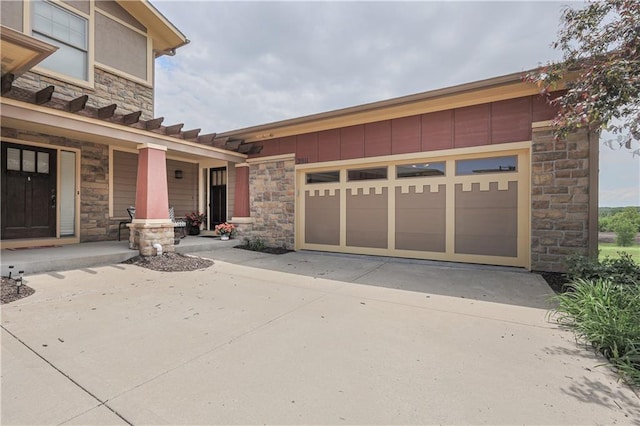 view of front facade with stone siding, driveway, covered porch, and an attached garage