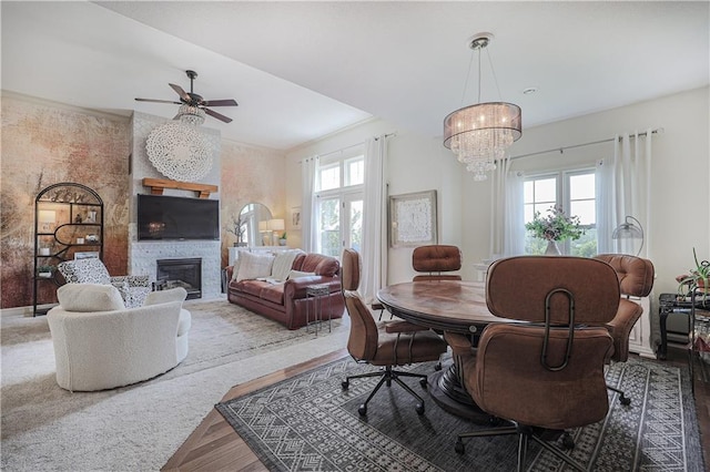 dining area featuring healthy amount of natural light, a chandelier, a fireplace, and ceiling fan