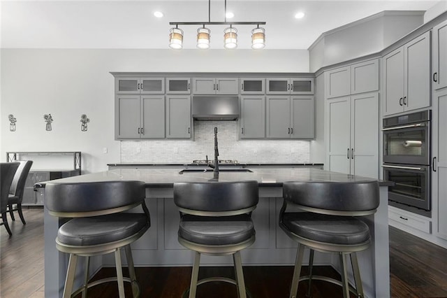 28897 Hackberry Cir, Paola, KS 66071 - kitchen with gray cabinets, under cabinet range hood, tasteful backsplash, an island with sink, and recessed lighting