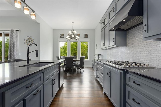 28897 Hackberry Cir, Paola, KS 66071 - kitchen featuring under cabinet range hood, a sink, a chandelier, stainless steel appliances, and gray cabinetry