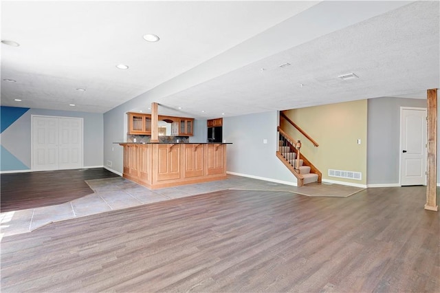 6330 N Nevada Ave, Parkville, MO 64152 - unfurnished living room with wood finished floors, baseboards, stairway, recessed lighting, and bar area