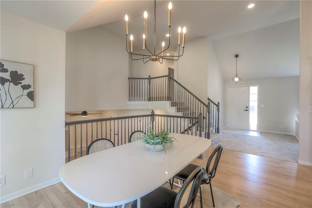 1102 Manse Dr, Raymore, MO 64083 - dining area featuring baseboards, wood finished floors, stairway, a chandelier, and high vaulted ceiling