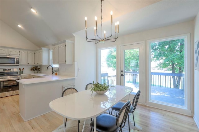 1102 Manse Dr, Raymore, MO 64083 - dining area featuring a chandelier, plenty of natural light, lofted ceiling, and light wood-style flooring