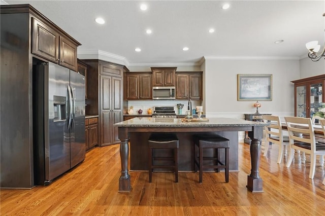 17311 Blue Moon Ln, Tonganoxie, KS 66086 - kitchen with stainless steel appliances, ornamental molding, stone countertops, dark brown cabinetry, and a kitchen island with sink