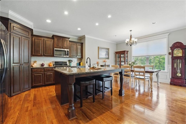 17311 Blue Moon Ln, Tonganoxie, KS 66086 - kitchen featuring stainless steel appliances, a kitchen breakfast bar, a chandelier, light wood-style flooring, and a center island with sink