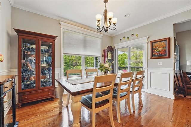 17311 Blue Moon Ln, Tonganoxie, KS 66086 - dining room featuring a chandelier, a wainscoted wall, light wood-style floors, ornamental molding, and a decorative wall