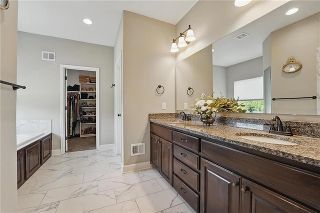 17311 Blue Moon Ln, Tonganoxie, KS 66086 - bathroom featuring marble look tiles, double vanity, baseboards, a walk in closet, and a bath