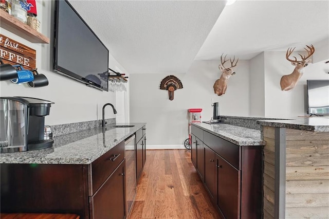 17311 Blue Moon Ln, Tonganoxie, KS 66086 - kitchen with a sink, wood finished floors, baseboards, light stone countertops, and dark brown cabinets