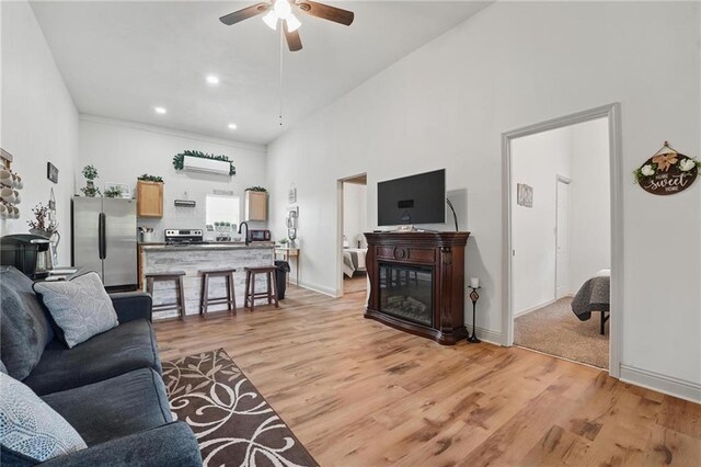 17311 Blue Moon Ln, Tonganoxie, KS 66086 - living area with a ceiling fan, light wood finished floors, a glass covered fireplace, a towering ceiling, and baseboards