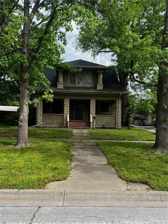 315 W 4th St, Ottawa, KS 66067 - view of front of house with covered porch, stone siding, and a front yard