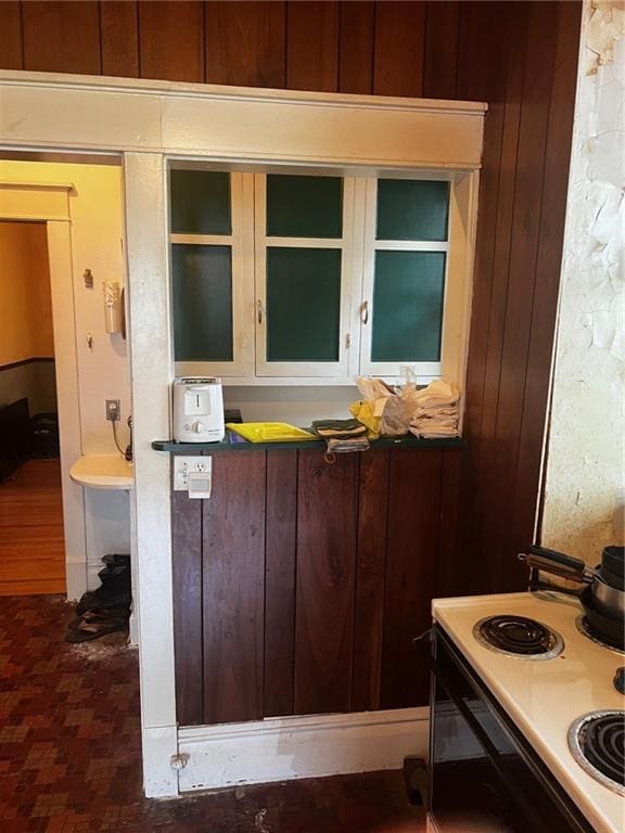 315 W 4th St, Ottawa, KS 66067 - kitchen view of range with electric cooktop, wooden walls, and glass insert cabinets
