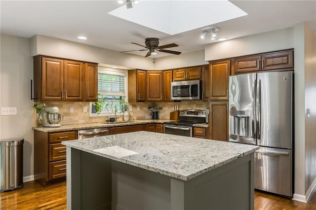 kitchen with appliances with stainless steel finishes, a sink, light stone countertops, dark wood-style floors, and ceiling fan