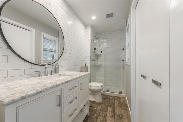 full bath featuring wood finished floors, a shower stall, toilet, vanity, and recessed lighting