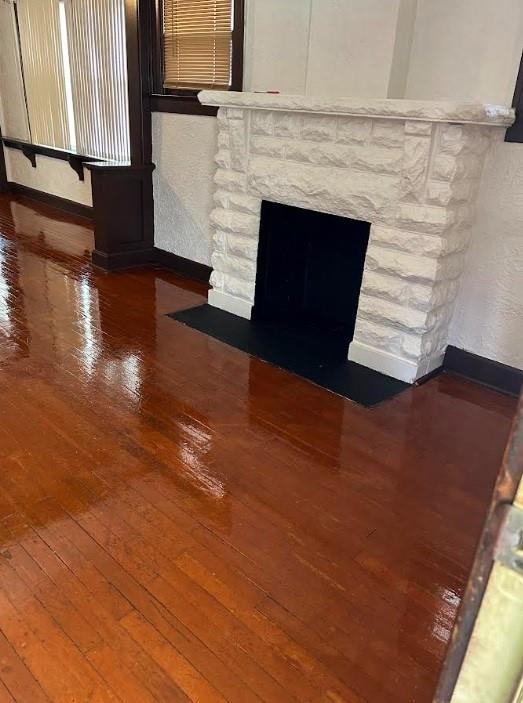 3637 Bales Ave, Kansas City, MO 64128 - detailed view of wood finished floors, a stone fireplace, and baseboards