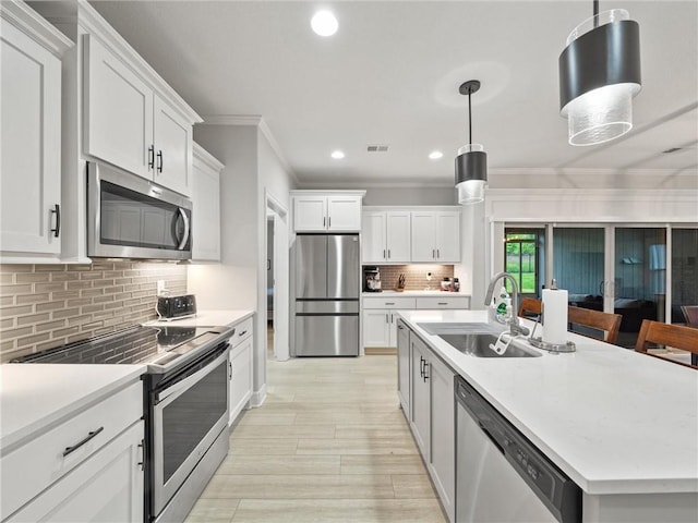 11382 S Longview Rd, Olathe, KS 66061 - kitchen featuring stainless steel appliances, crown molding, light countertops, white cabinetry, and a kitchen island with sink
