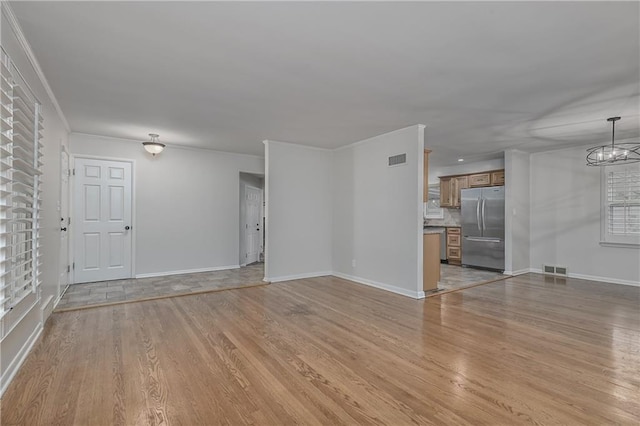 6411 Outlook Dr, Mission, KS 66202 - unfurnished living room with light wood-type flooring, baseboards, a chandelier, and crown molding
