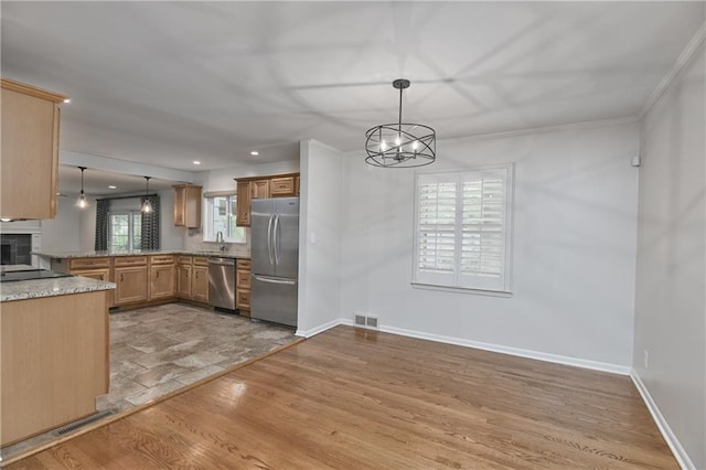 6411 Outlook Dr, Mission, KS 66202 - kitchen with appliances with stainless steel finishes, a sink, a chandelier, light wood finished floors, and decorative light fixtures