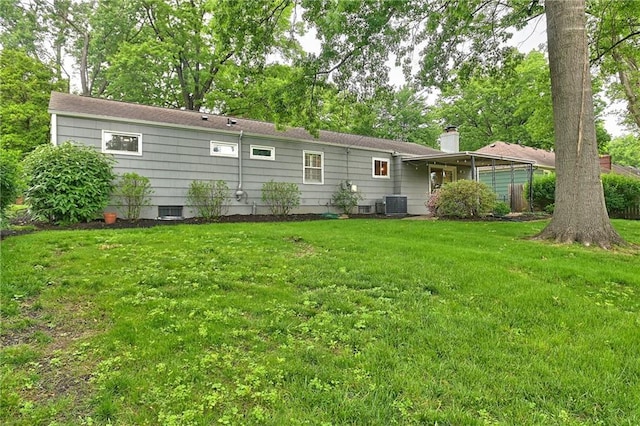 6411 Outlook Dr, Mission, KS 66202 - rear view of property featuring central AC unit, a lawn, and a chimney