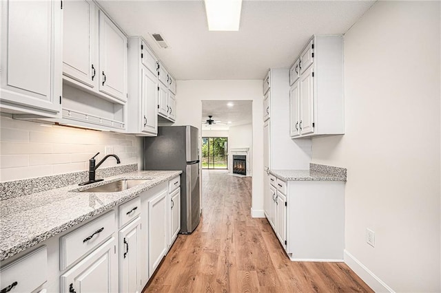 kitchen featuring a sink, freestanding refrigerator, light wood-type flooring, and ceiling fan