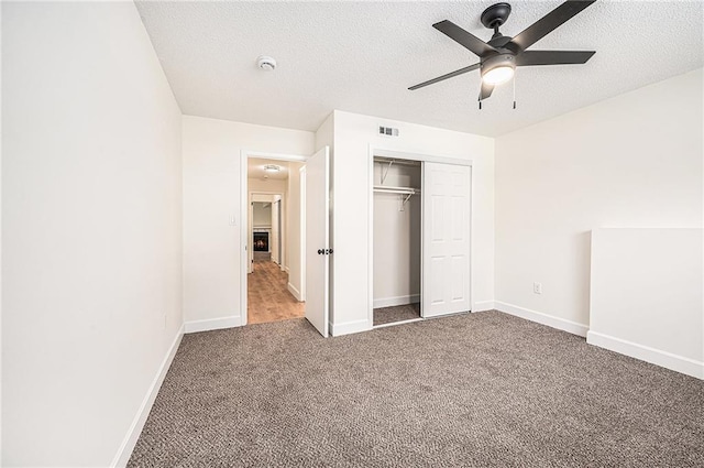 unfurnished bedroom with carpet flooring, a closet, a textured ceiling, baseboards, and a ceiling fan