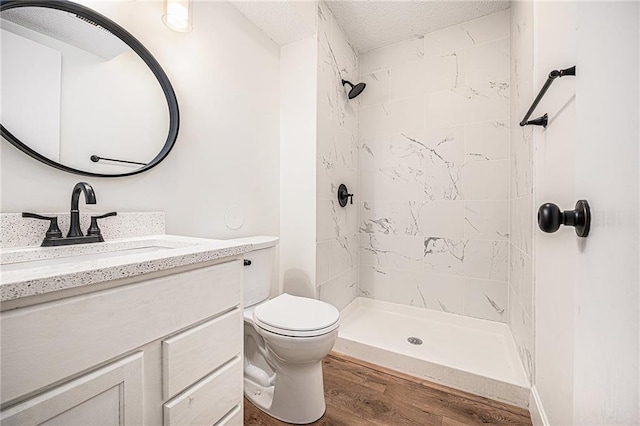 full bath with vanity, wood finished floors, a shower stall, toilet, and a textured ceiling