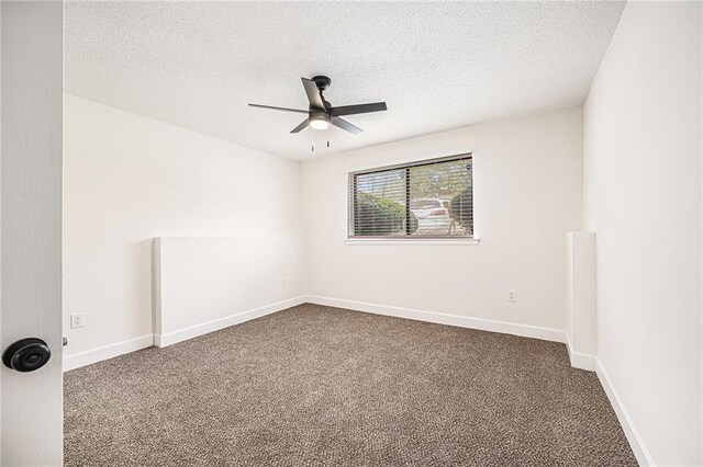 unfurnished room featuring ceiling fan, dark carpet, a textured ceiling, and baseboards