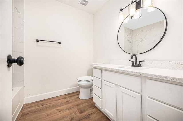 full bathroom featuring baseboards, wood finished floors, vanity, and toilet