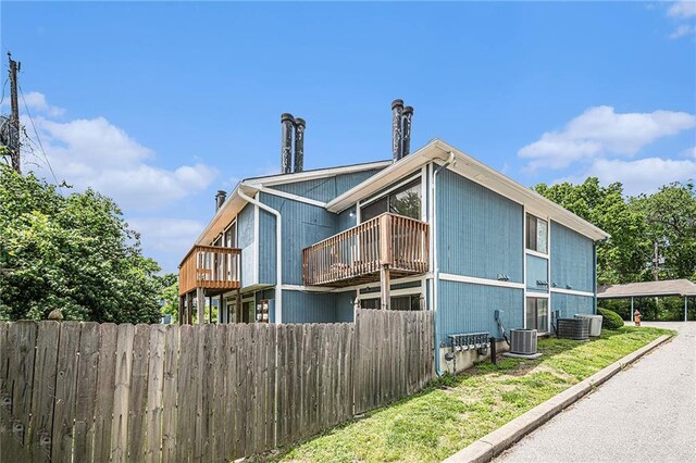 view of side of property featuring fence, central air condition unit, and a balcony