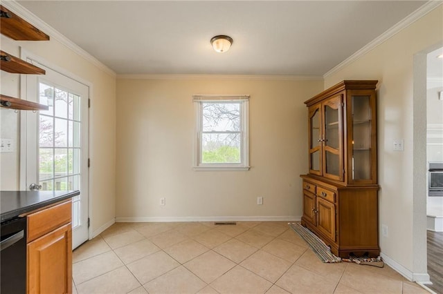 unfurnished dining area featuring ornamental molding, light tile patterned floors, and baseboards