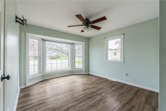 empty room featuring dark wood-type flooring, baseboards, and ceiling fan