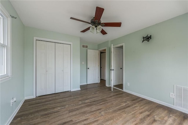 unfurnished bedroom featuring wood finished floors, baseboards, a closet, and ceiling fan