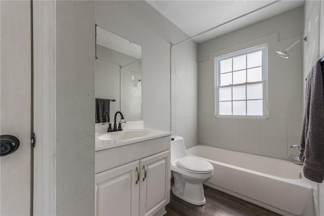 bathroom featuring toilet, vanity, wood finished floors, and shower / washtub combination