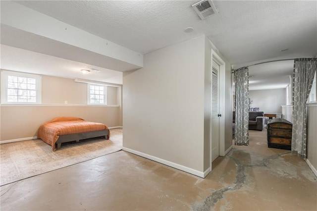 bedroom featuring baseboards, concrete floors, a textured ceiling, and a closet