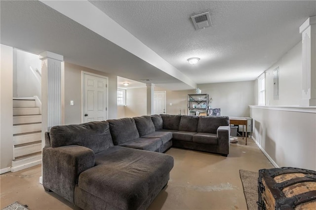 living room featuring ornate columns, finished concrete floors, a textured ceiling, baseboards, and stairs