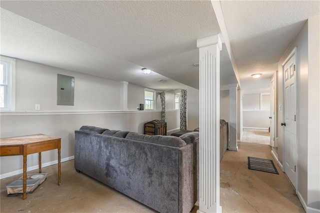 living room with ornate columns, electric panel, a textured ceiling, concrete flooring, and baseboards