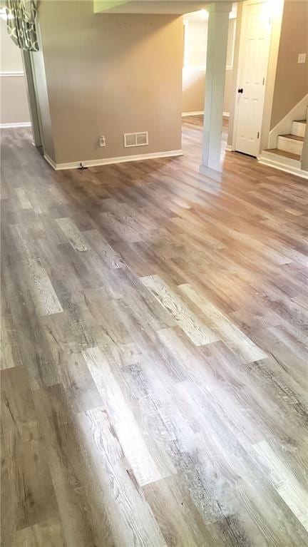 spare room featuring wood finished floors, stairway, and baseboards